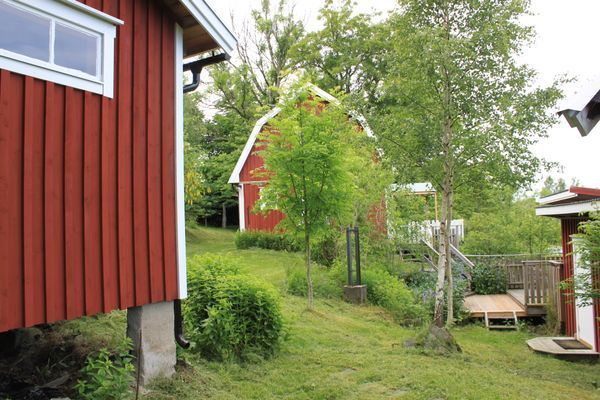 Huset sett från dasset, söderifrån, delvis tak (duk) över altanen för skuggan och som skydd vid lätt regn