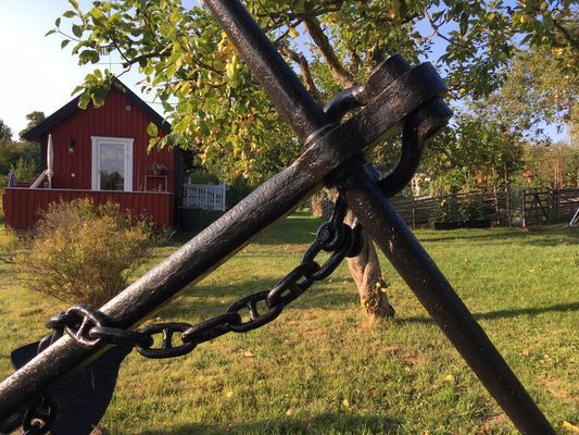 Ankare i trädgården med stugan i bakgrunden