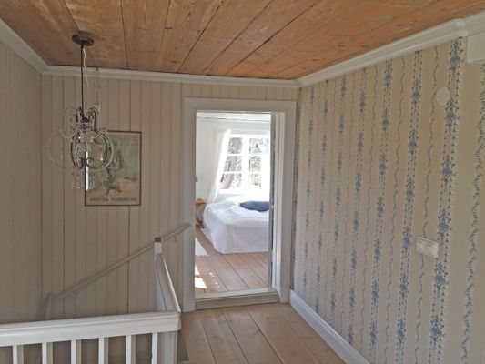 Hall övervåning samt dörr in till sovrum 1 med dubbelsäng.