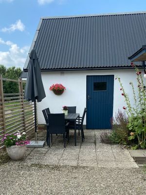 Litet hus vid fruktodling och hage.